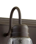 Close-up of one light on the Transitional Five Light Vanity Fixture in Oiled Bronze with Clear and Seeded Glass Damp Rated Bathroom Lighting 36 Inch