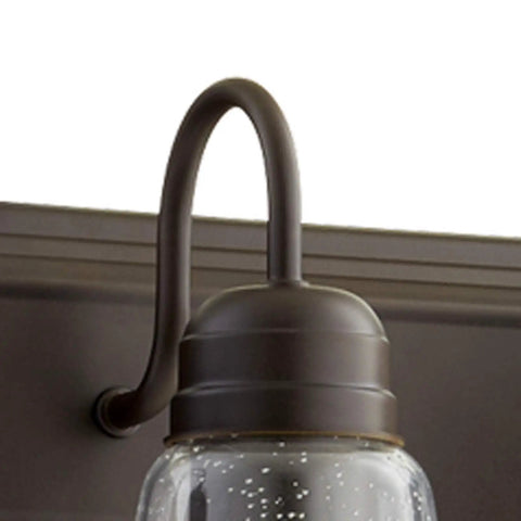 Close-up of one light on the Transitional Five Light Vanity Fixture in Oiled Bronze with Clear and Seeded Glass Damp Rated Bathroom Lighting 36 Inch