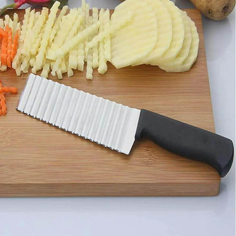 Top view of stainless steel crinkle-cut potato knife with black handle on cutting board