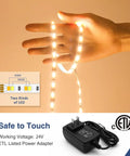 52.5ft 24V Dimmable Led Strip Lights Tunable White 3000K to 6000K Remote Controlled, held in a hand, with power adapter