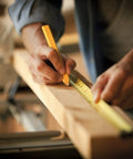 Person measuring wood with 25 Ft Measuring Tape With Easy Read Decimal Scale, Dual Sided Ruler In Metric And Inches, Magnetic Tip