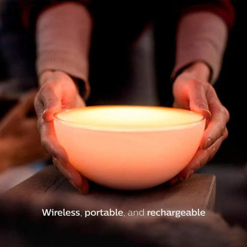 Hands holding a glowing Go White And Color Portable Dimmable LED Smart Light Table Lamp That Plays Nice With Alexa HomeKit And Google Assistant