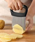 Crinkle cutter with stainless steel blades and black ergonomic handle, slicing potatoes into crinkle-cut fries.