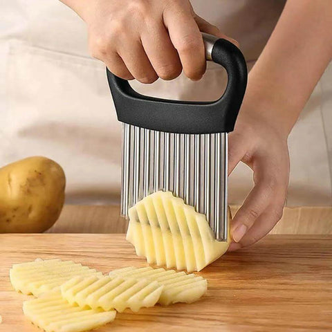 Crinkle cutter with stainless steel blades and black ergonomic handle, slicing potatoes into crinkle-cut fries.