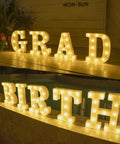 Must Have Light Up Letters Marquee Signs For Wedding Party And Home Decor, LED letter lights on display reading 'GRAD' and 'BIRTH'