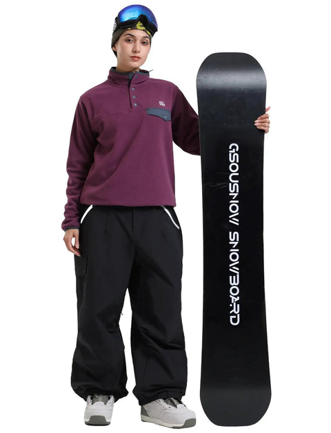 Person with snowboard wearing Baggy Snow Pants for Women and Men Insulated Snowboarding Trousers Waterproof Windproof Outdoor Gear Black Loose Fit