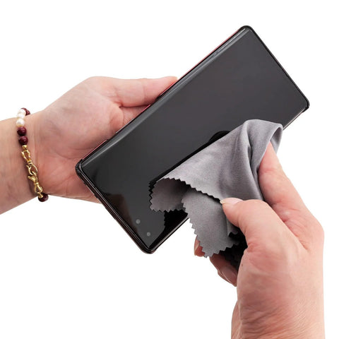 Gray microfiber cleaning cloth for smartphone screens, hand wiping a smartphone display
