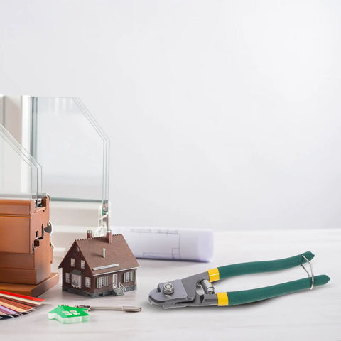 Pro Multi-Functional Cable Stripping Pliers With Ergonomic Handle For Precise Wire Gauge Adjustment next to a miniature house, tools, and plans.