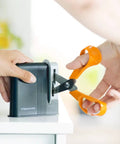 Using Clip Sharp Scissors Sharpener For All Scissors, Quick No Fuss Sharpening, Extends Shears Life on a pair of orange scissors.