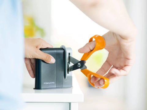 Using Clip Sharp Scissors Sharpener For All Scissors, Quick No Fuss Sharpening, Extends Shears Life on a pair of orange scissors.