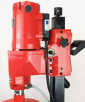 Concrete core drill, red motor unit on black stand with hose and controls