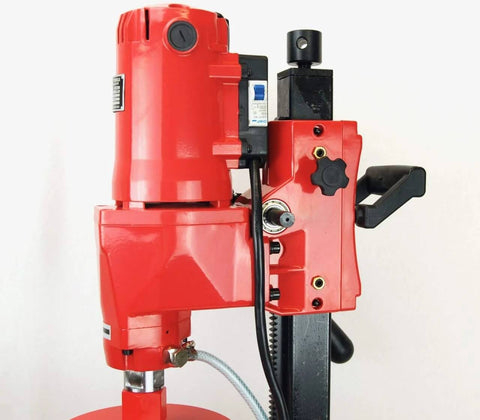 Concrete core drill, red motor unit on black stand with hose and controls