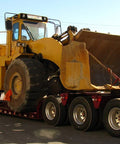 Beefed Up Heavy Duty Chain Binder Kit With Three Eighths Inch By Ten Foot Chains securing loader on trailer for transport