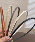 Premium Skinny Leather Headbands For Women Five Piece Set in soft neutral shades held in hand, showcasing non-slip minimalist fit.