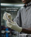MICROFLEX MF-300 disposable latex gloves with textured fingertips worn by a worker in a gray shirt.