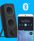 Bluetooth 2.0 Desktop Speakers With 3.5mm Aux Cable next to smartphone showing music app on blue background