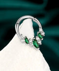 Green gemstone septum ring with clear crystals on white display, silver toned, lightweight stainless steel body