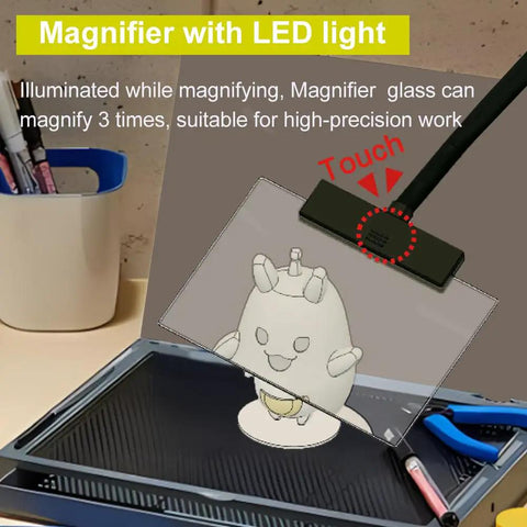 Portable Model Making Workbench With LED Lights And Magnifier All In One Cutting And Assembly Kit For DIYers Includes Pliers Holder Gridded Adhesive Cut Mats Plastic Storage Drawers Display Panel top view with magnifier and tools.