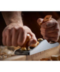 Close-up of hands using Low Angle Jack Plane, Sweetheart No 64 Style, Old School Pro Hand Tool for flattening wood, showing precise shaves.