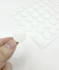 Close-up of a hand holding a round PVC sticker from the White Screw Hole Cover Set including 290 pieces in three sizes.