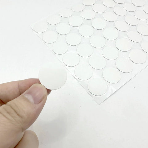 Close-up of a hand holding a round PVC sticker from the White Screw Hole Cover Set including 290 pieces in three sizes.