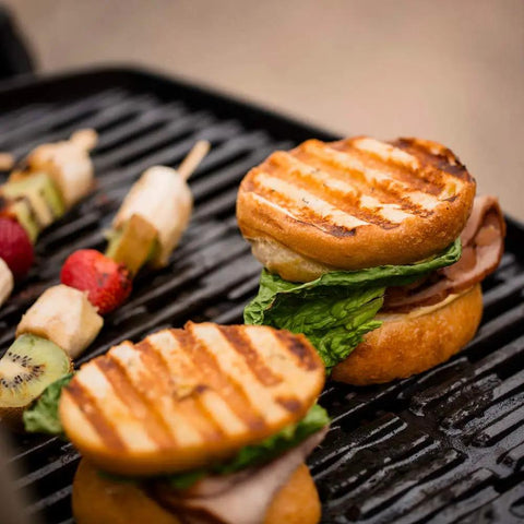 Grilled burgers and skewers on Q1200 Portable Propane Grill For Travel And Camping Blue With 1 Burner Cast Iron Grates Electronic Ignition 8500 BTU Ideal For Tailgating Backyards Campsites And Picnics Compact Reliable Outdoor Grilling On The Go