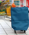 Collapsible Shopping Cart With 360 Degree Swivel Wheels For Travel And Home in lake blue beside a grocery cart, showing side view.