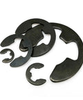 Pro Grade Black Steel External Retaining Ring Set For Shafts E Type And C Type Circlips DIN6799 Sizes M2 To M24 Including M2.5 M3 M3.5 M4 M5 M6 M7 M8 M9 M10 M11 M12 M13 M15 M19 M22 M24 Available In 10, 50, And 100 Packs, shown in various sizes on a white background.