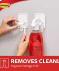 Hands installing a Spray Bottle Hangers Set With Two Mounts And Four Strips Holds Up To 32 Fl Oz Damage Free Wall Mount on a gray wall.