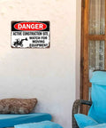 Funny Metal Sign Danger Active Construction Site Aluminum Sign 8x12 Inch displayed on outdoor wall near chairs.