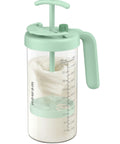The Go To Rock Solid Borosilicate Glass Breast Milk Pitcher With 32 Oz And Upgraded Bpa Free Mixing Spoon For Heat Safe No Sweat Nursing Mom Storage view, featuring a light green mixing spoon and measurement markings.
