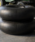 Stack of Heavy Duty 2 Pack Inner Tubes for 15x6-6 Lawn Mower and Golf Cart Wheels with Straight Valve, garage background.