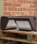 BUTIFULSIC Outdoor Security Flood Light 2 Pack Brown Aluminum Dusk to on wooden pallet against brick wall.