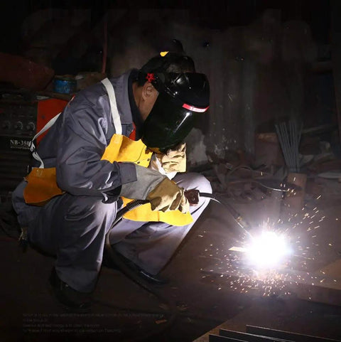Welder using Auto Darkening Welding Helmet With Shade 9 For Argon Arc And Gas Shielded Welding, crouched with sparks flying