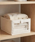 Heavy Duty Cotton Linen Foldable Storage Bins Stackable Closet Organizers with blankets stored in a beige fabric bin on a shelf.