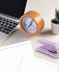 Heavy-Duty Single Hole Punch For Up To Fifteen Sheets, purple metal handheld paper punch on desk with laptop, clock, and plant.