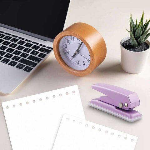 Heavy-Duty Single Hole Punch For Up To Fifteen Sheets, purple metal handheld paper punch on desk with laptop, clock, and plant.