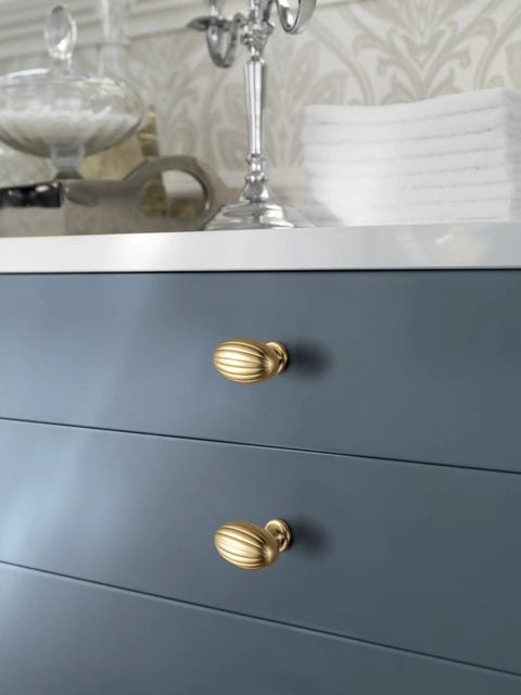 Oval Fluted Zinc Alloy Cabinet Knobs In Champagne Bronze on blue dresser drawers in a retro kitchen setting