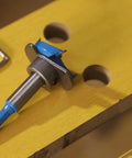 Badass Hex Shank Forstner Drill Bit Set With Carbide Tips And Adjustable Depth Ring on yellow wood, showcasing precision tooling.