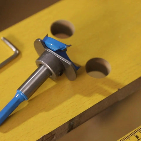 Badass Hex Shank Forstner Drill Bit Set With Carbide Tips And Adjustable Depth Ring on yellow wood, showcasing precision tooling.