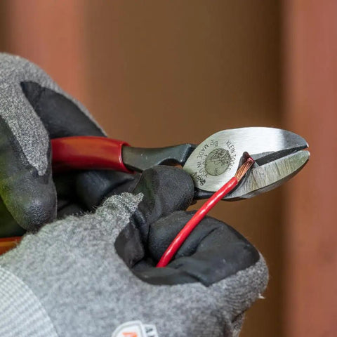 Close-up of 1104 BX Cable Cutter and All Purpose Shears cutting red wire, showcasing high leverage, one-hand operation.