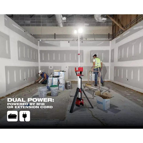 2136-20 Cordless Tripod Light For 18V M18 Rocket System illuminating a construction site with workers, adjustable to 7 feet