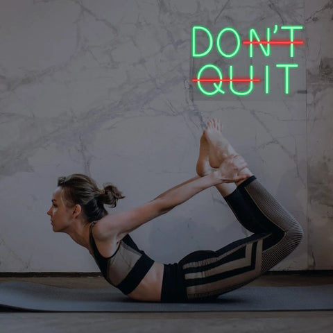 Woman doing yoga beside Neon Sign With Remote Stay Motivated Wall Decor 11.8 By 17.3 Inch Green Led Neon Light For Home Gym Office Bedroom Motivational Wall Art That Keeps You Pushing.