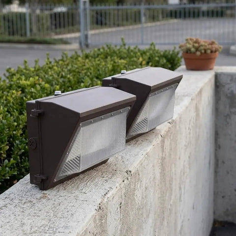 LIFKOME Outdoor Security Flood Light 2 Pack Aluminum Dusk to IP66 mounted on wall with green shrub background.