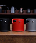 Heavy Duty Shock Absorbent Coffee Knock Box For Espresso Machines in black, red, and grey, designed for clean ground disposal.