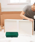 Big Boy Green Metal Toolbox with Rugged Carry Handle and Secure Latch Perfect for Garage Organization and Truck Bed Runs Features Plenty of Room to Sort Out Hammer Screwdriver Pliers Drill and More Making Home Repairs and Auto Fixes a Breeze, positioned in the foreground as a man assembles furniture.