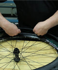 Person installing Bike Tire Liners And Protectors Lightweight Puncture Proof Set For 12 To 26 Inch Tires on a bike wheel.