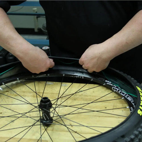 Person installing bike tire liners and protectors lightweight puncture proof set for 12 to 26 inch tires on wheel rim.