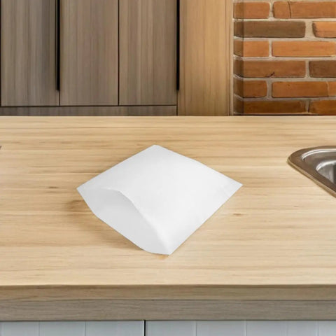 Single white EPE foam packing pouch on wooden countertop, part of 25 pack, shockproof cushion bag for fragile dishes and glassware.