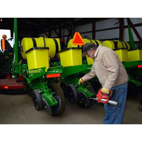 Man using M18 Cordless Grease Gun Kit With Chrome Finish, High Pressure Lubrication Tool For Auto, Farm, And Workshop in barn